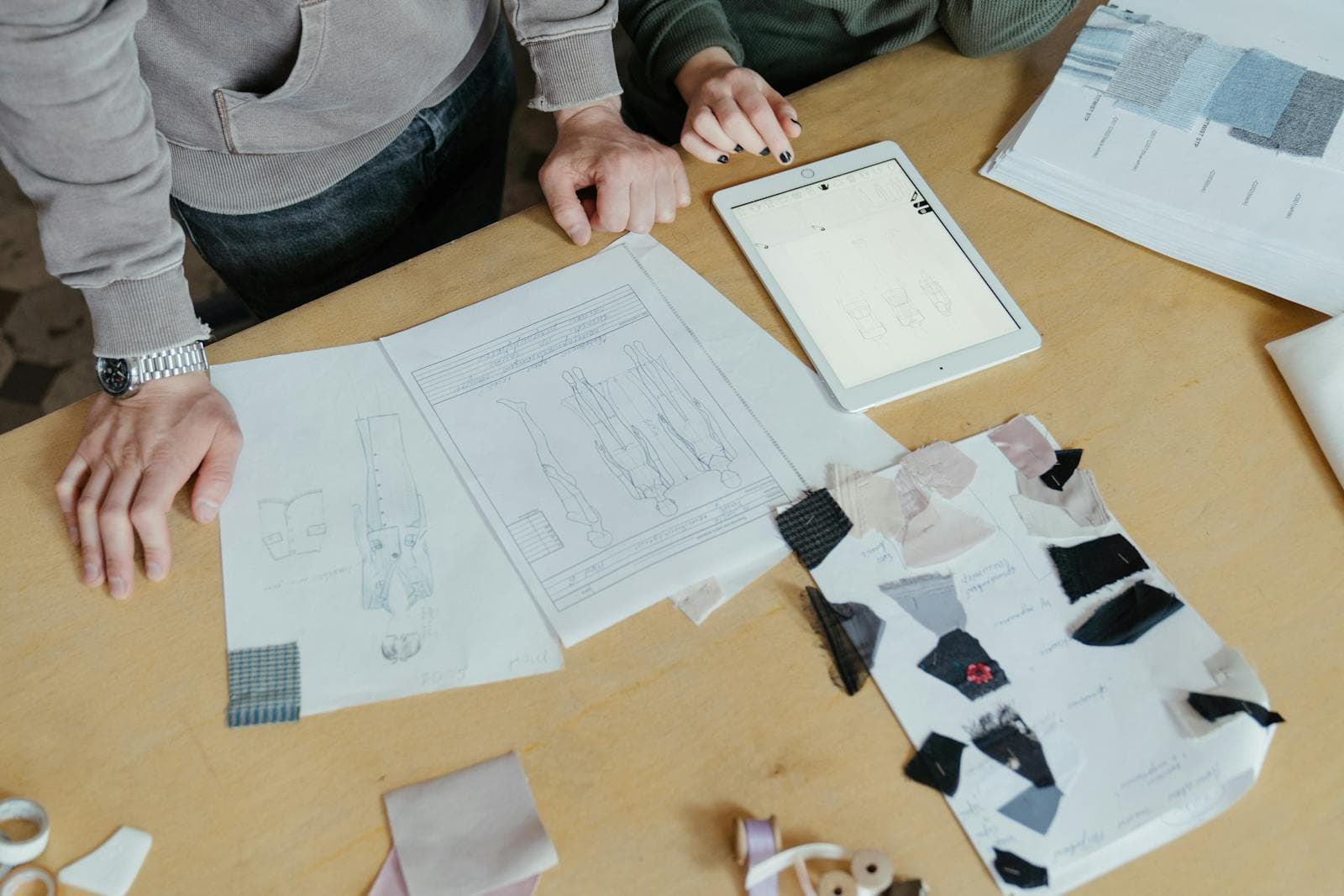 Designers planning garments with sketches and fabric at a worktable